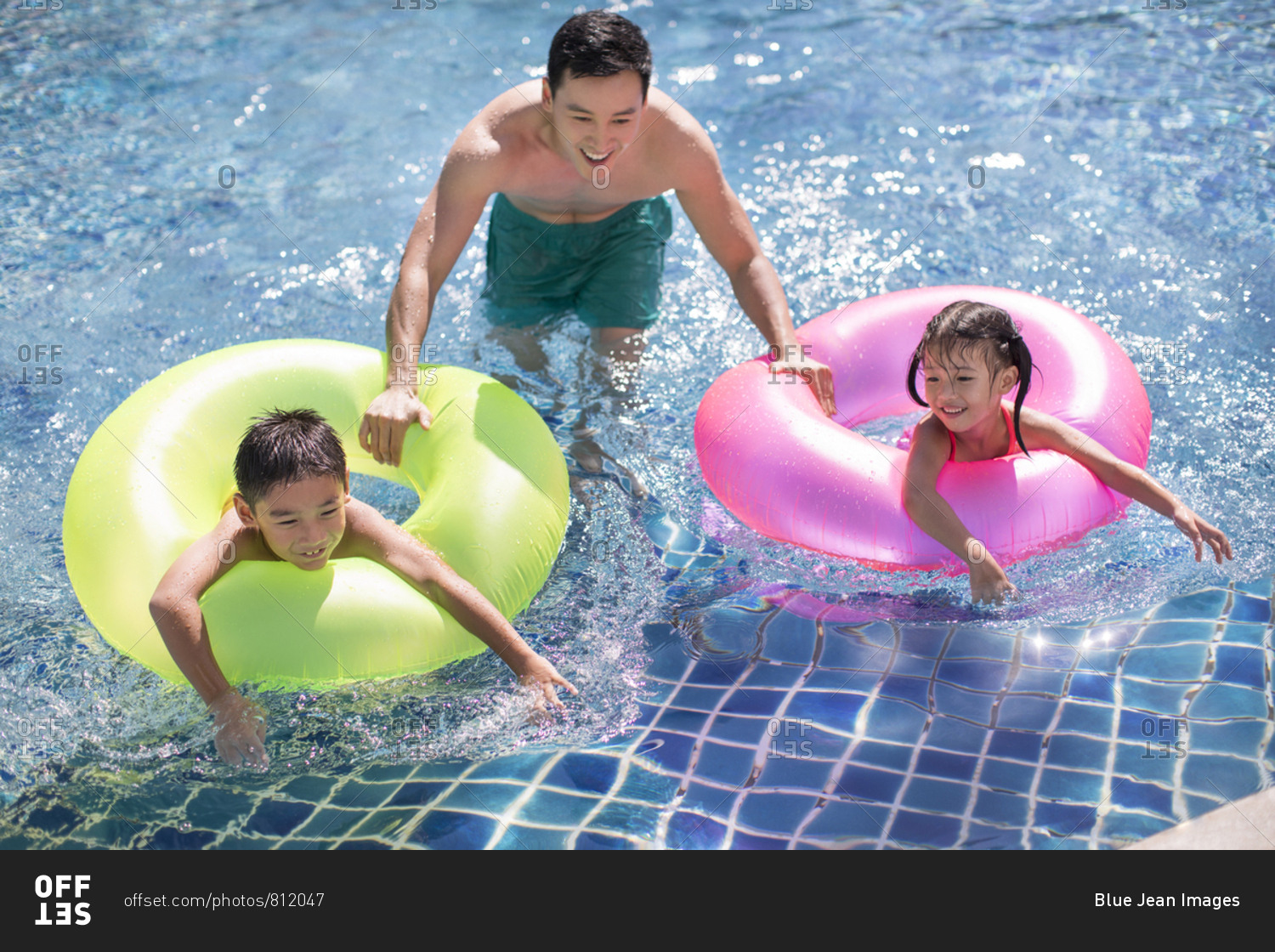 Happy young family playing in swimming pool