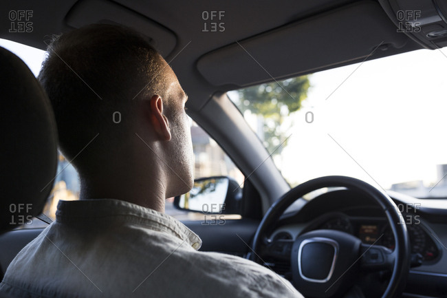 Rear view of young man driving car at sunset