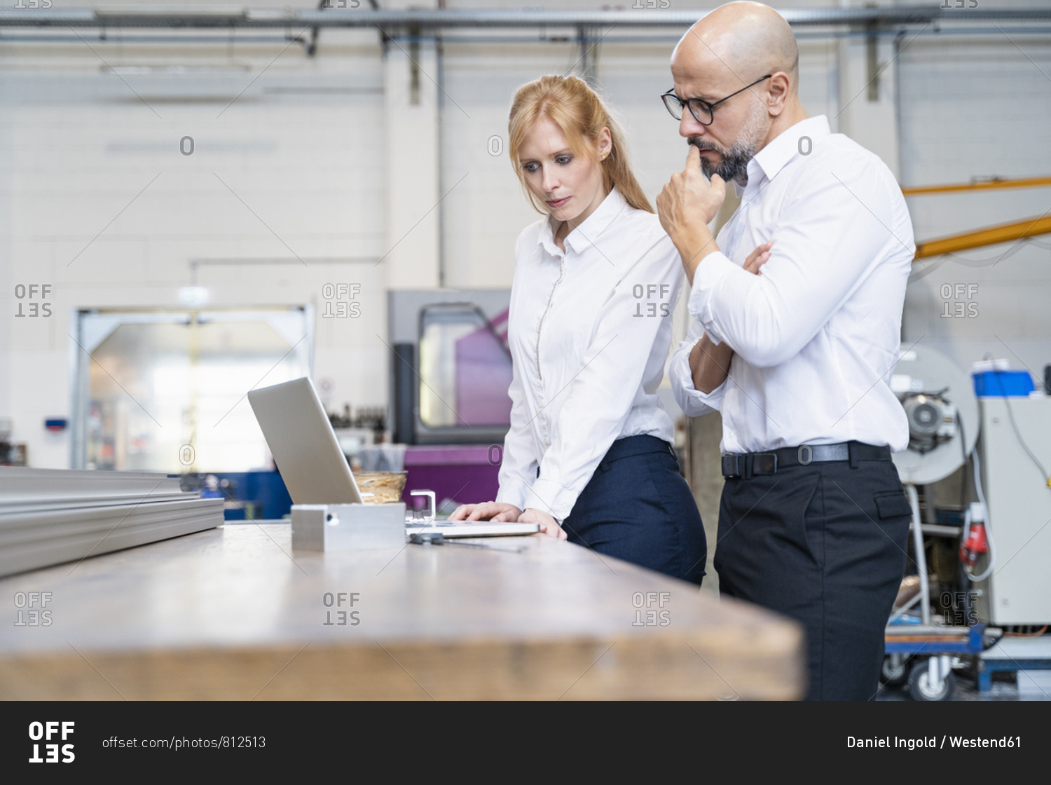 Businessman and businesswoman using laptop in factory