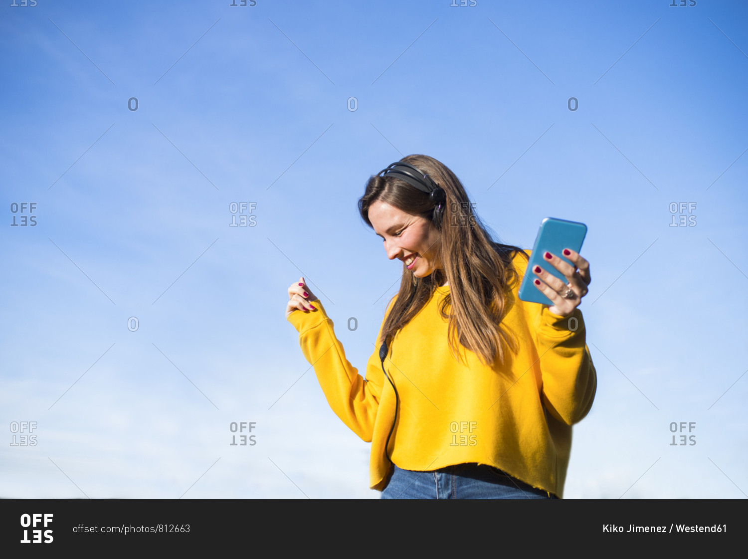 Happy young woman with cell phone listening to music with headphones