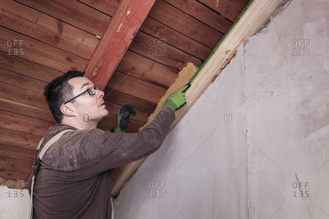 Roof insulation- worker filling pitched roof with wood fiber insulation