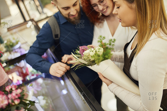 Florist wrapping flowers for couple in flower shop