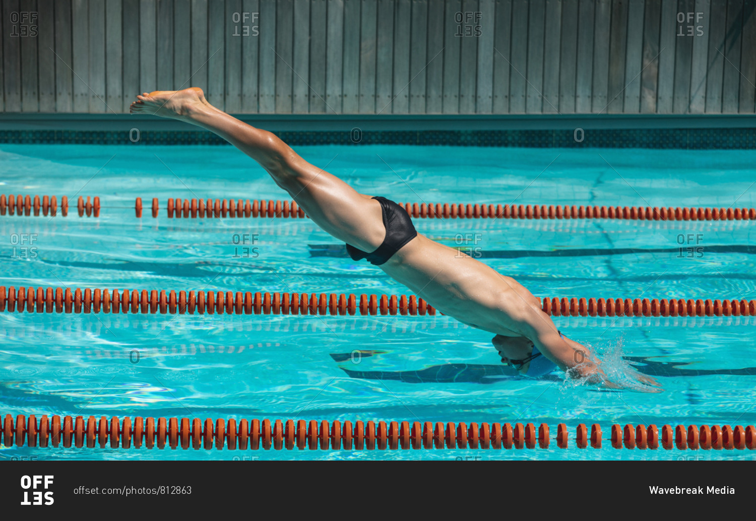 Young male swimmer jumping into water of a swimming pool stock photo