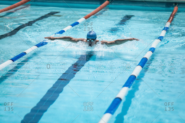 Young Caucasian male swimmer swimming butterfly stroke in swimming pool