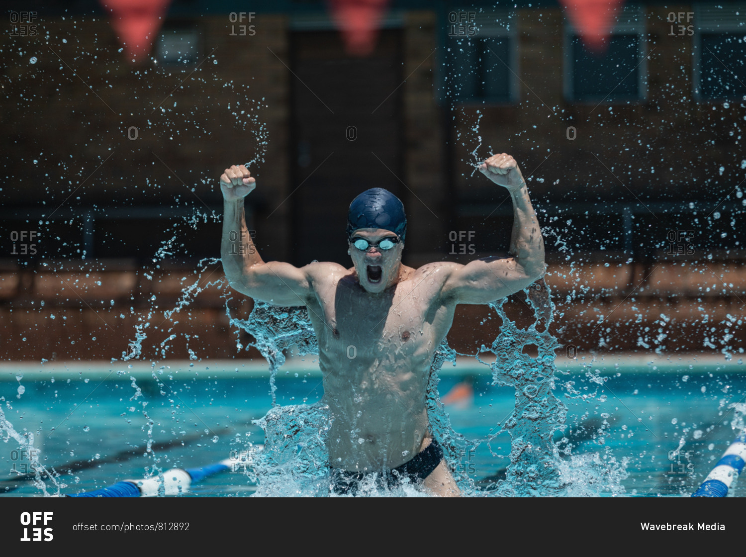 Young swimmer with arms up celebrate victory in pool stock photo - OFFSET