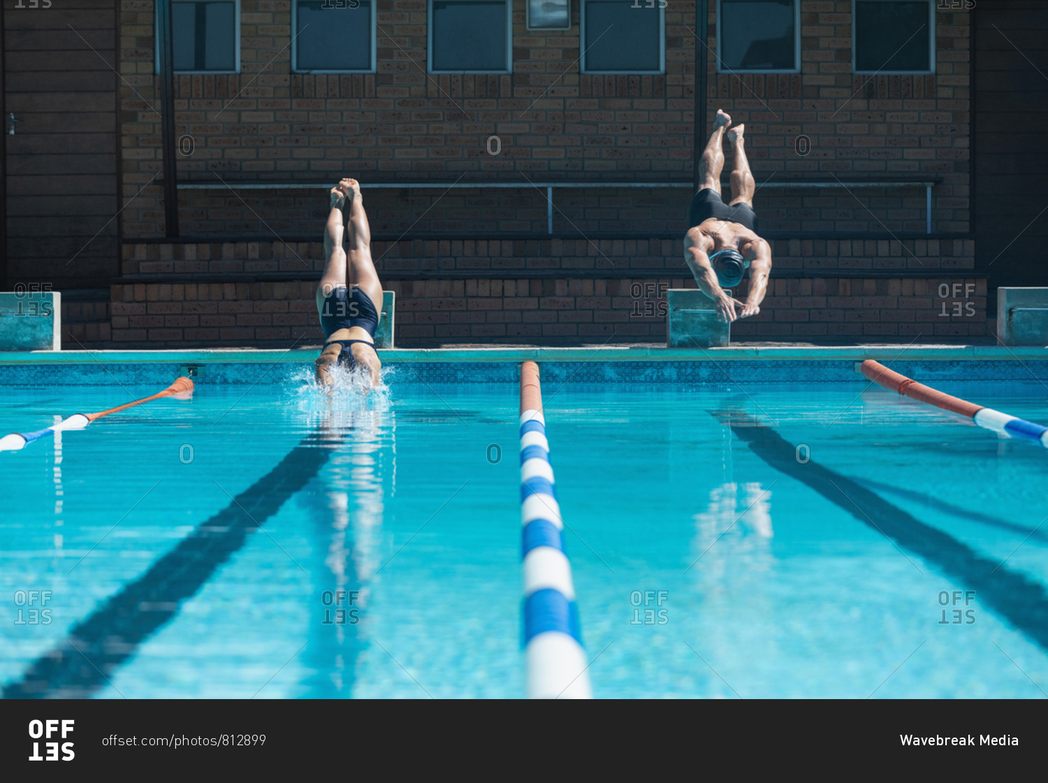 Young swimmers jumping into water at swimming pool stock photo OFFSET