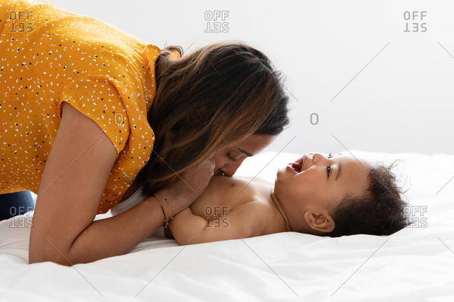Mother kissing her smiling baby on tummy