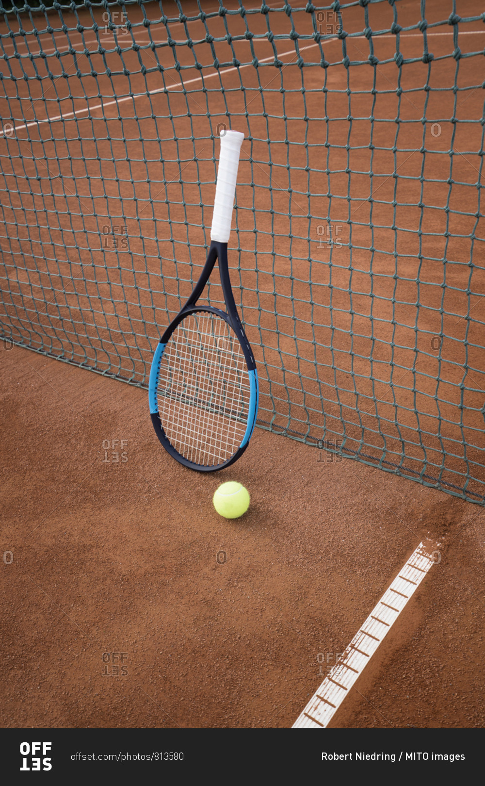 Tennis ball with racket leaning on net of tennis court, Bavaria, Germany