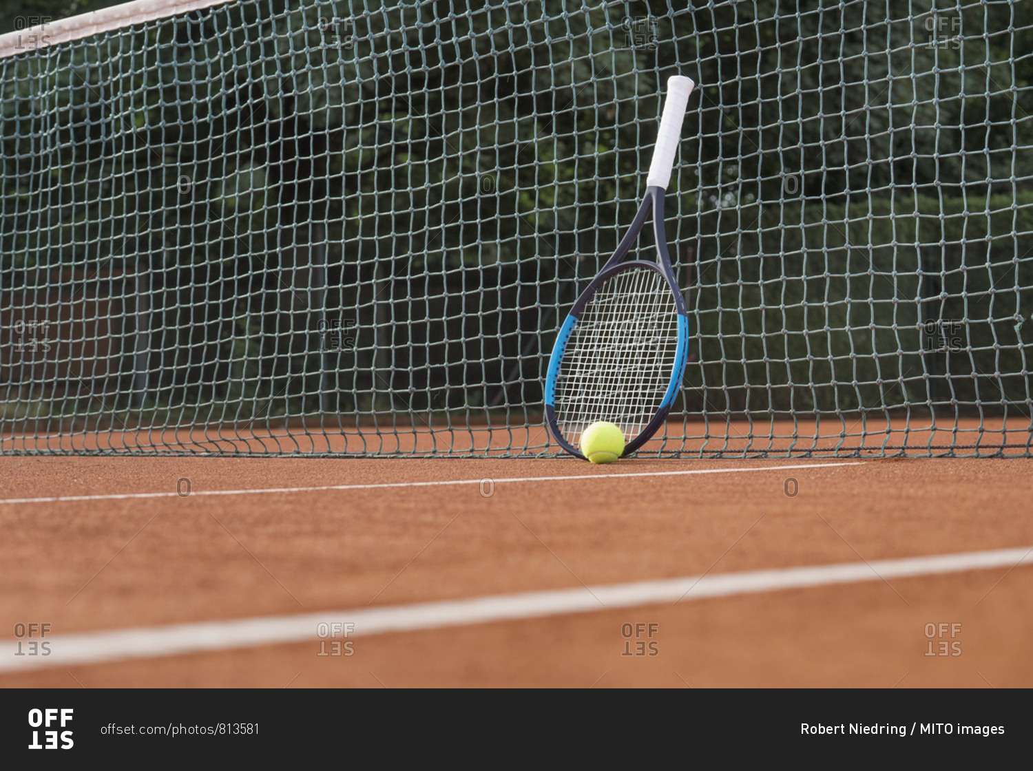 Tennis ball with racket leaning on net of tennis court, Bavaria, Germany