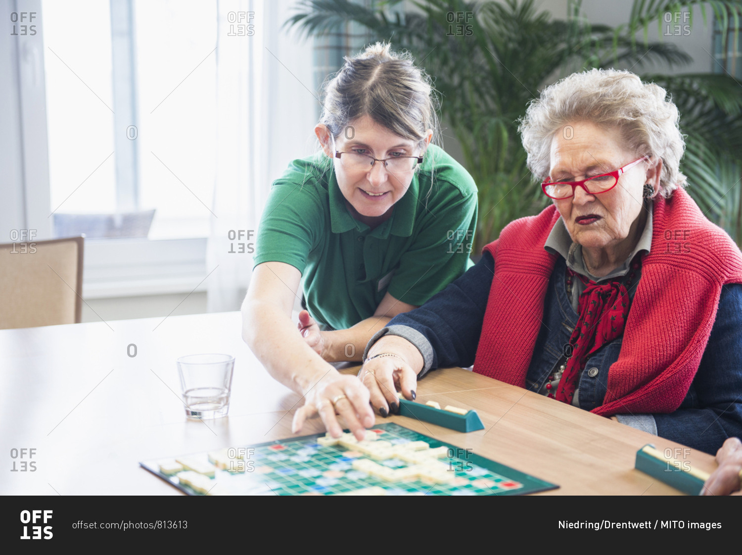 Nursing staff assisting senior woman playing scrabble board game
