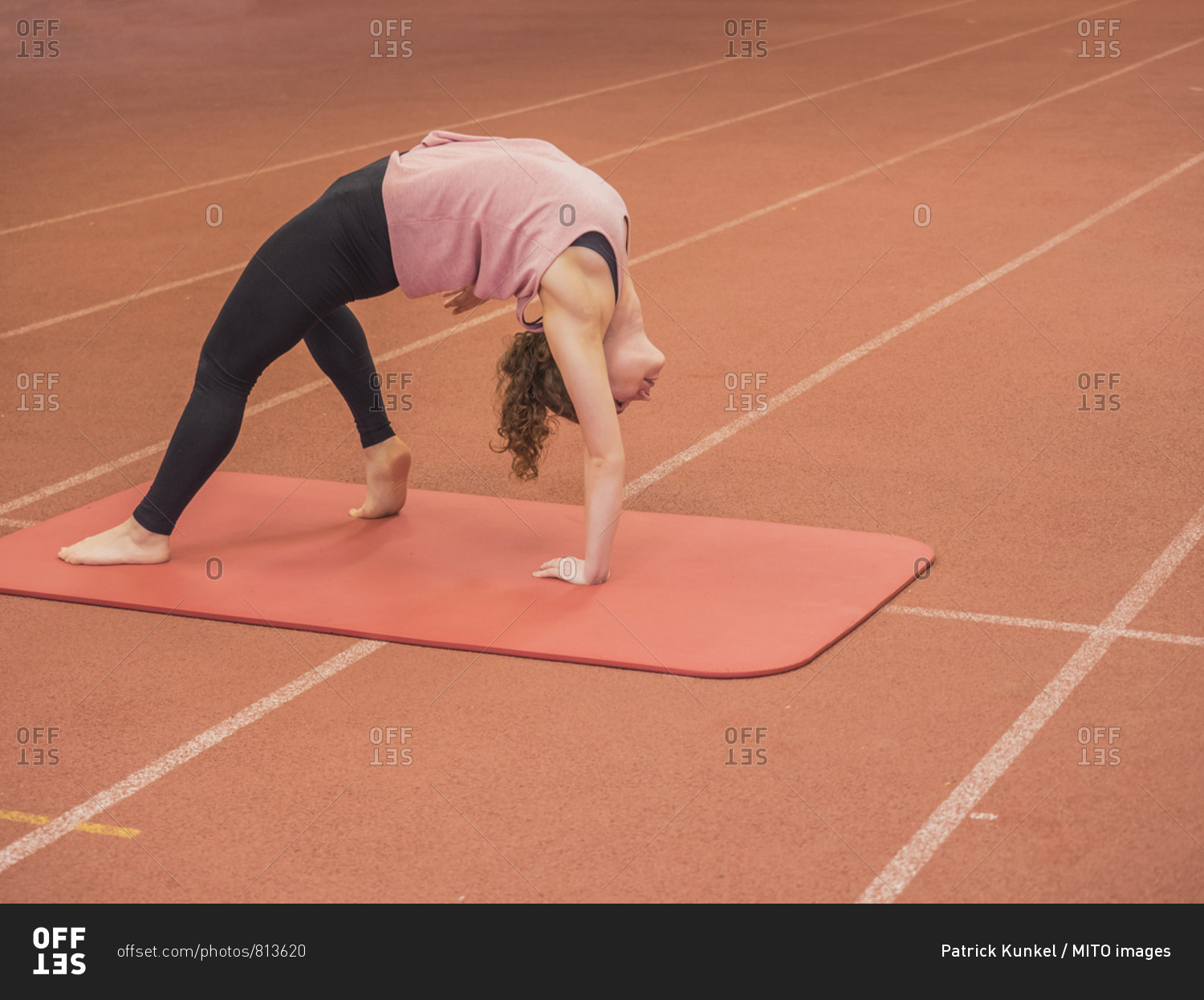 Woman bending over backwards in yoga position at athletics hall on tartan track, Offenburg, Baden-Wurttemberg, Germany