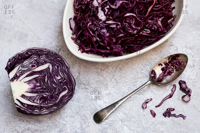 A dish of cooked red cabbage and half a raw cabbage.