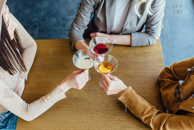 Overhead of three women in their early thirties having drinks at a restaurant