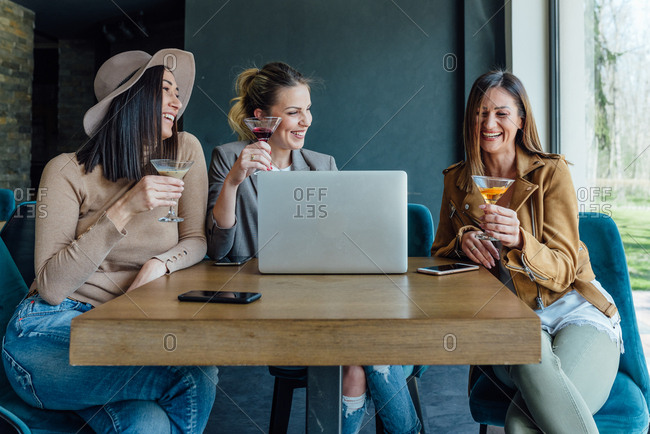 Three friends having fun at the restaurant drinking cocktails