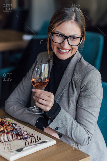 A business woman in her thirties enjoys a glass of wine with her lunch
