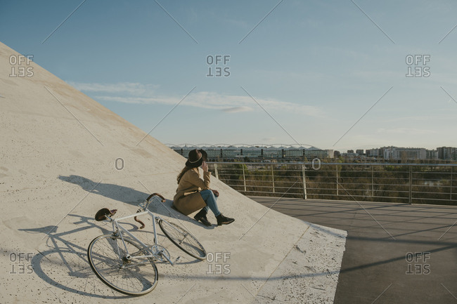 Young hipster woman sitting next to a bicycle