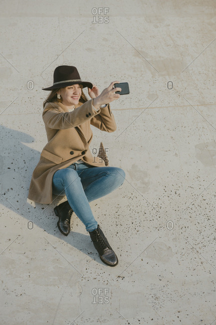 young hipster woman sitting on the ground making a selfie