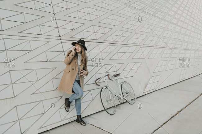 Young hipster woman speaking by phone near to a bicycle