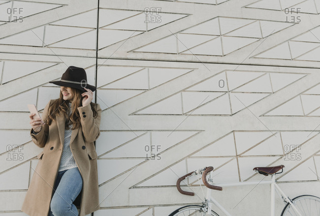 Young hipster woman near to a bicycle holding a phone