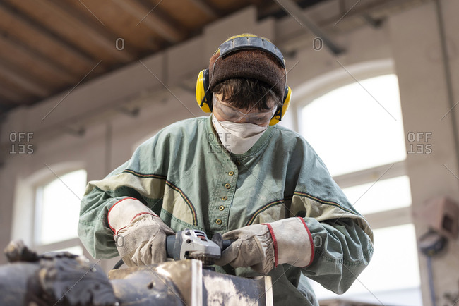 Art foundry- Female foundry worker polishing metal