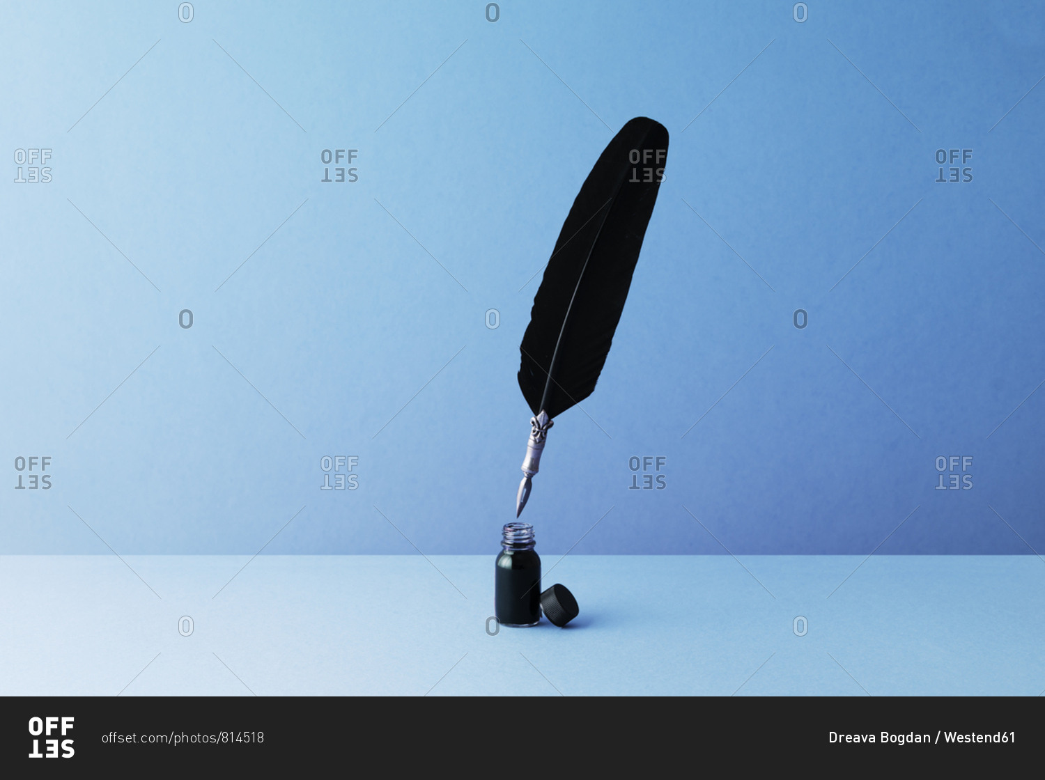 Quill pen and inkwell over blue background stock photo - OFFSET
