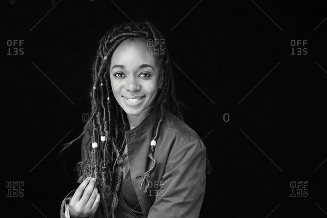 Portrait of smiling woman with dreadlocks in front of black background