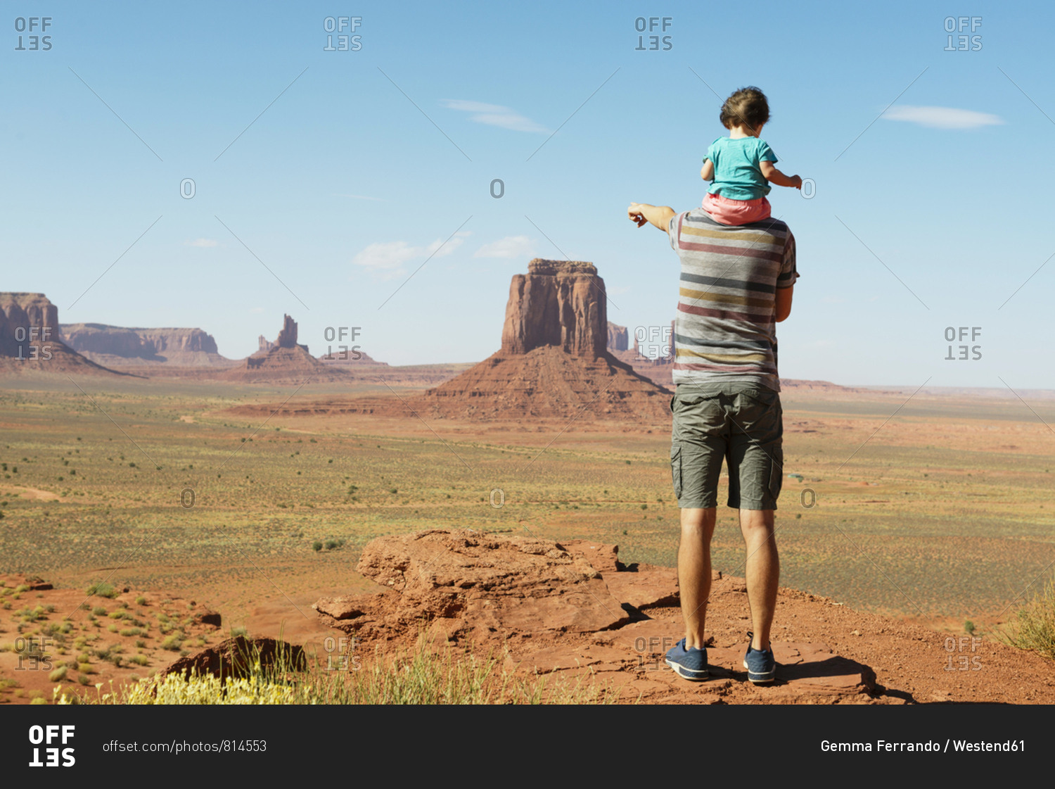 USA- Utah- Monument Valley- Father traveling with baby- girl on shoulders and pointing to Monument Valley landscape