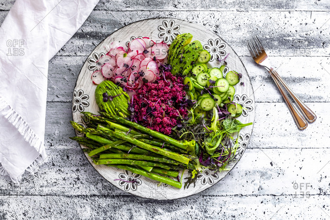Plate of springtime salad with green asparagus- red quinoa- avocado- red radishes- cucumber and sprouts