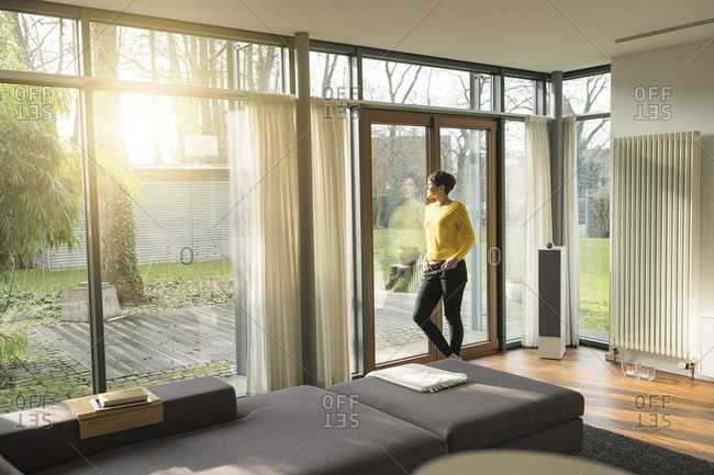 Woman Standing In Living Room In The Evening Looking Through