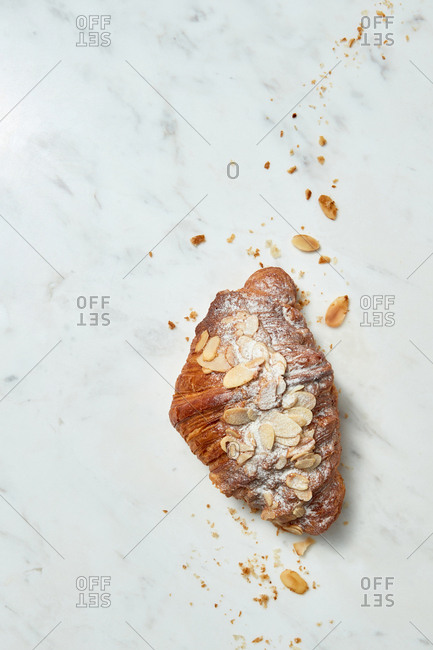 Delicious freshly baked French homemade croissant with almond crumbs on a gray marble background, copy space. Top view.