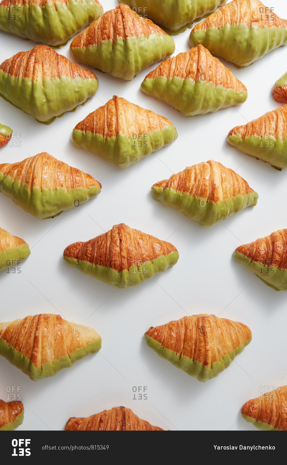 Fresh bakery pattern with French croissants covered in green glaze on a light gray background, copy space. Top view. Concept of breakfast continental.
