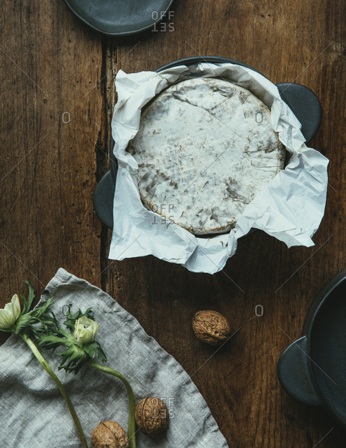 Camembert cheese on wooden table with walnuts