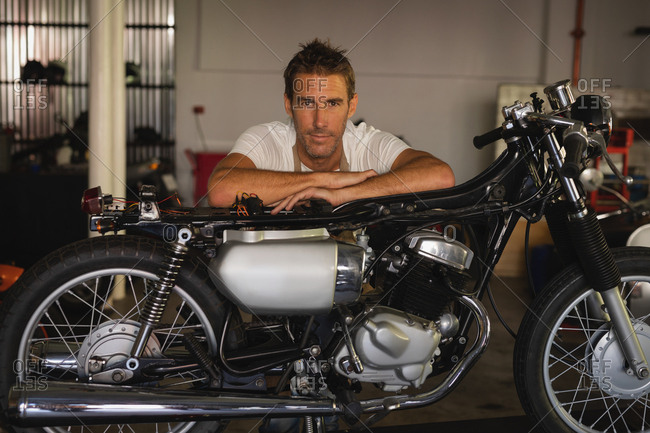 Portrait of Caucasian bike mechanic sitting with bike in garage