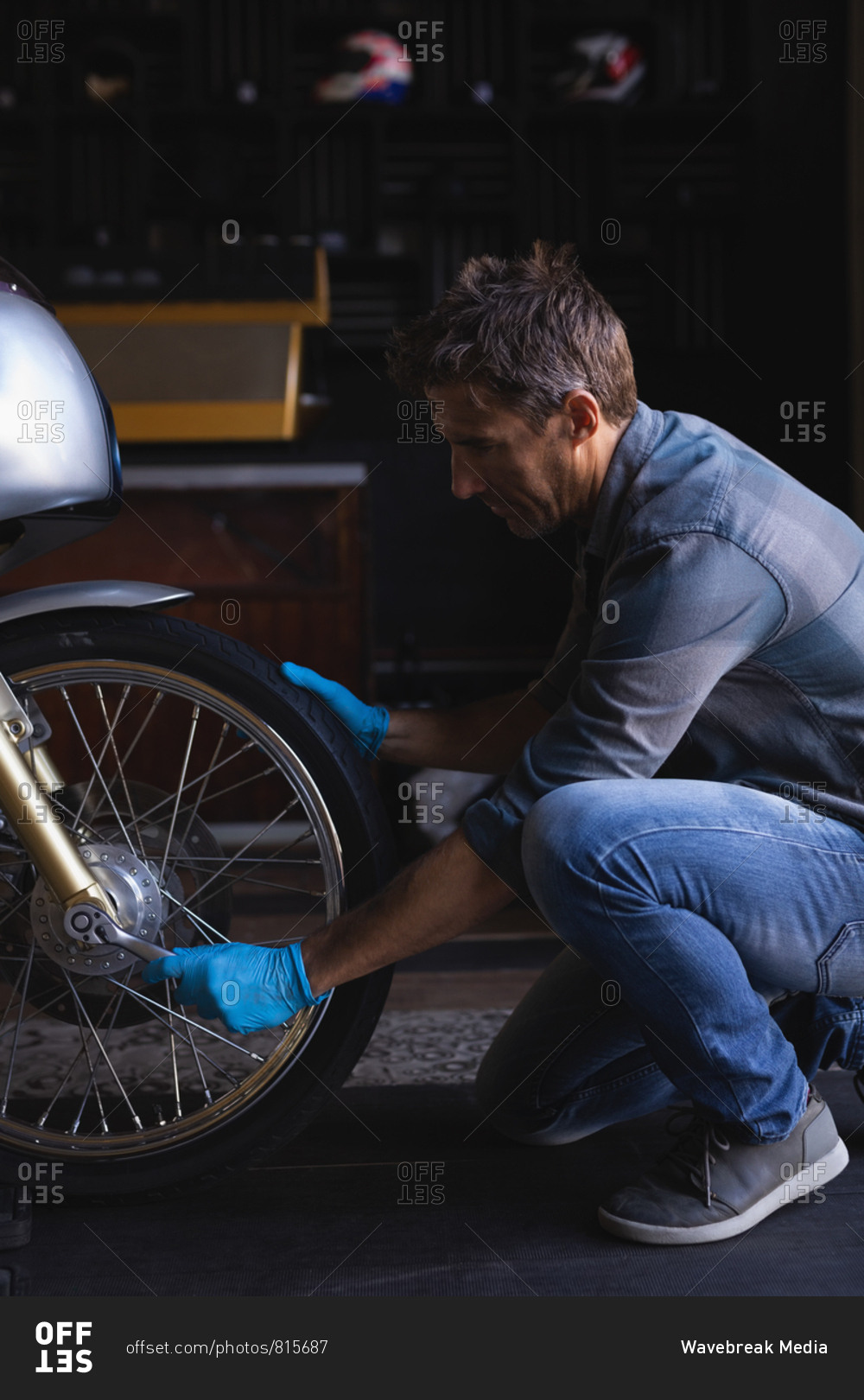 Side view of Caucasian bike mechanic using ratchet wrench to adjust bike tire