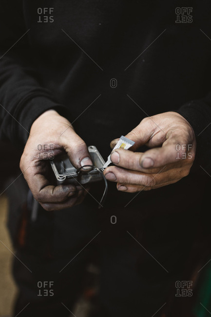 Unrecognizable repairman with dirty hands gluing broken part in workshop
