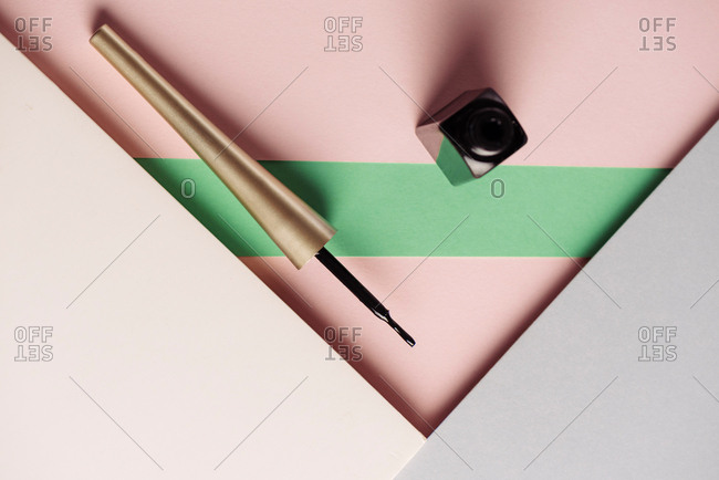 Liquid eyeliner brush, on attractive background, of pastel pink and green colors. Product and makeup concept. From above