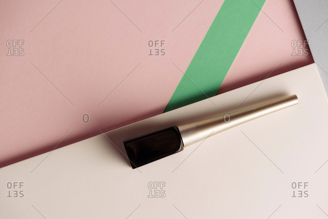 Liquid eyeliner brush, on attractive background, of pastel pink and green colors. Product and makeup concept. From above