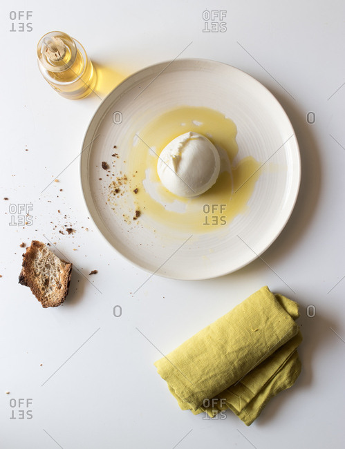 Plate with tasty burrata and piece of bread with oil on white background