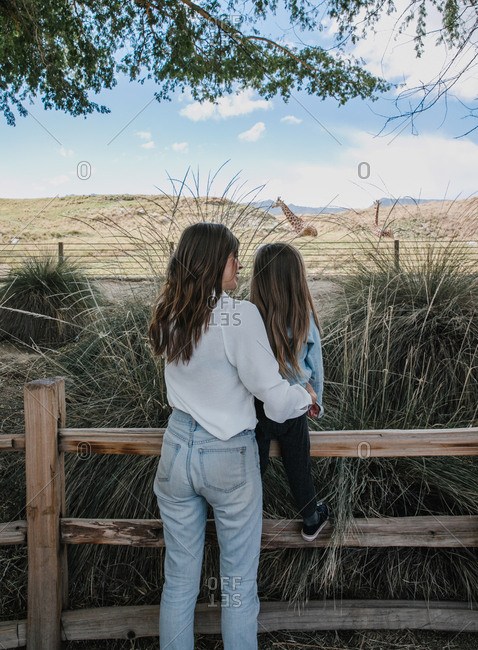 Mom and daughter looking at giraffes at the zoo
