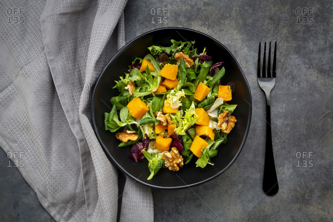Bowl of mixed green salad with hokkaido pumpkin and walnuts