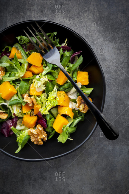 Bowl of mixed green salad with hokkaido pumpkin and walnuts