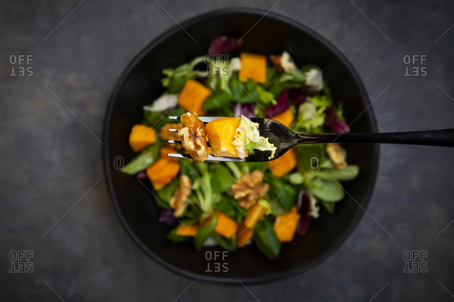Bowl of mixed green salad with hokkaido pumpkin and walnuts