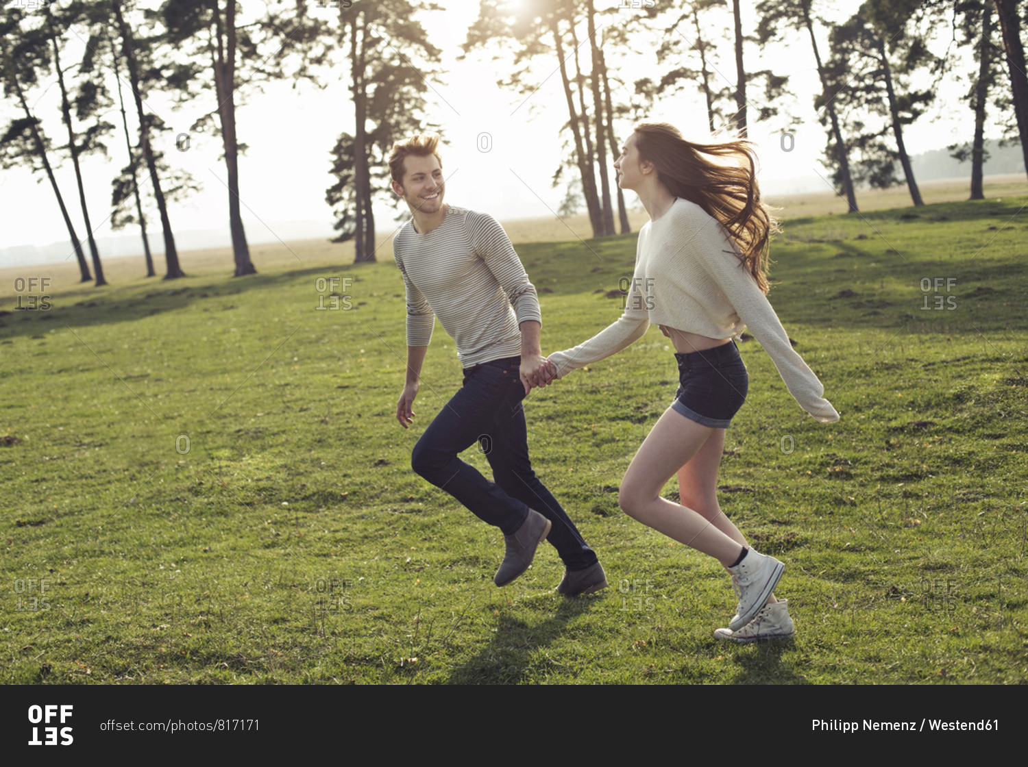 Happy young couple running hand in hand on meadow