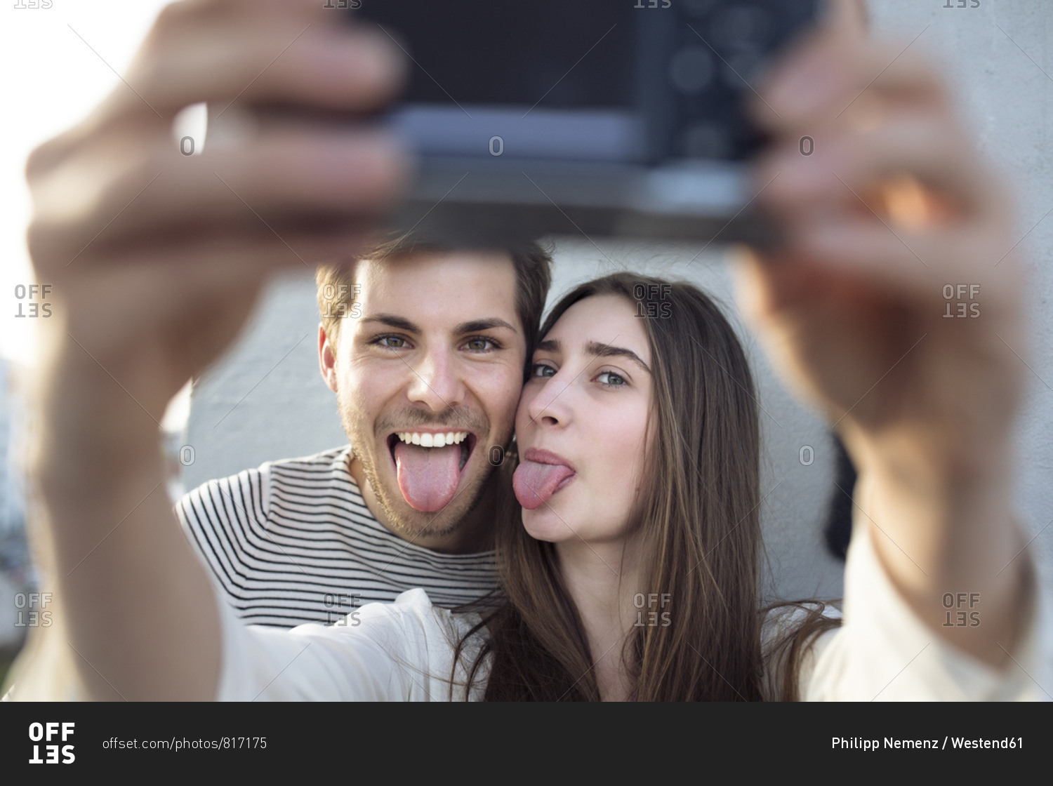 Playful young couple taking a selfie sticking tongues out