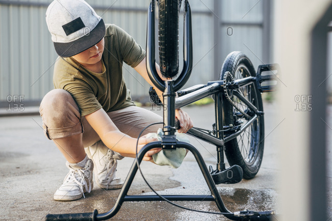 Boy cleaning bmx bike on yard