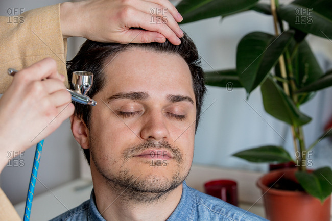 applying cosmetics on male face with airbrush