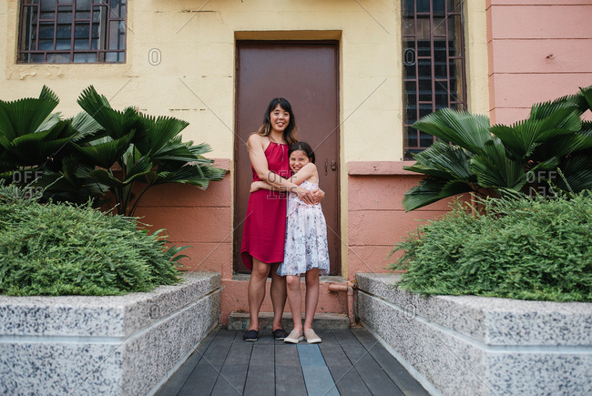 Mother and daughter posing in a hug outside a building in Kuala Lumpur