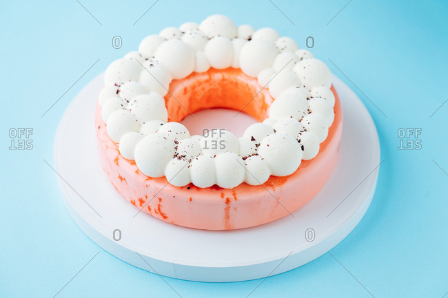 Round cake glazed with pink icing and meringue topping