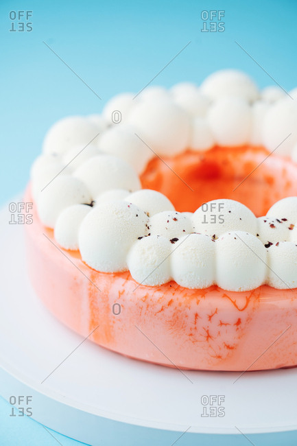 Close up of a round cake glazed with pink icing and meringue topping