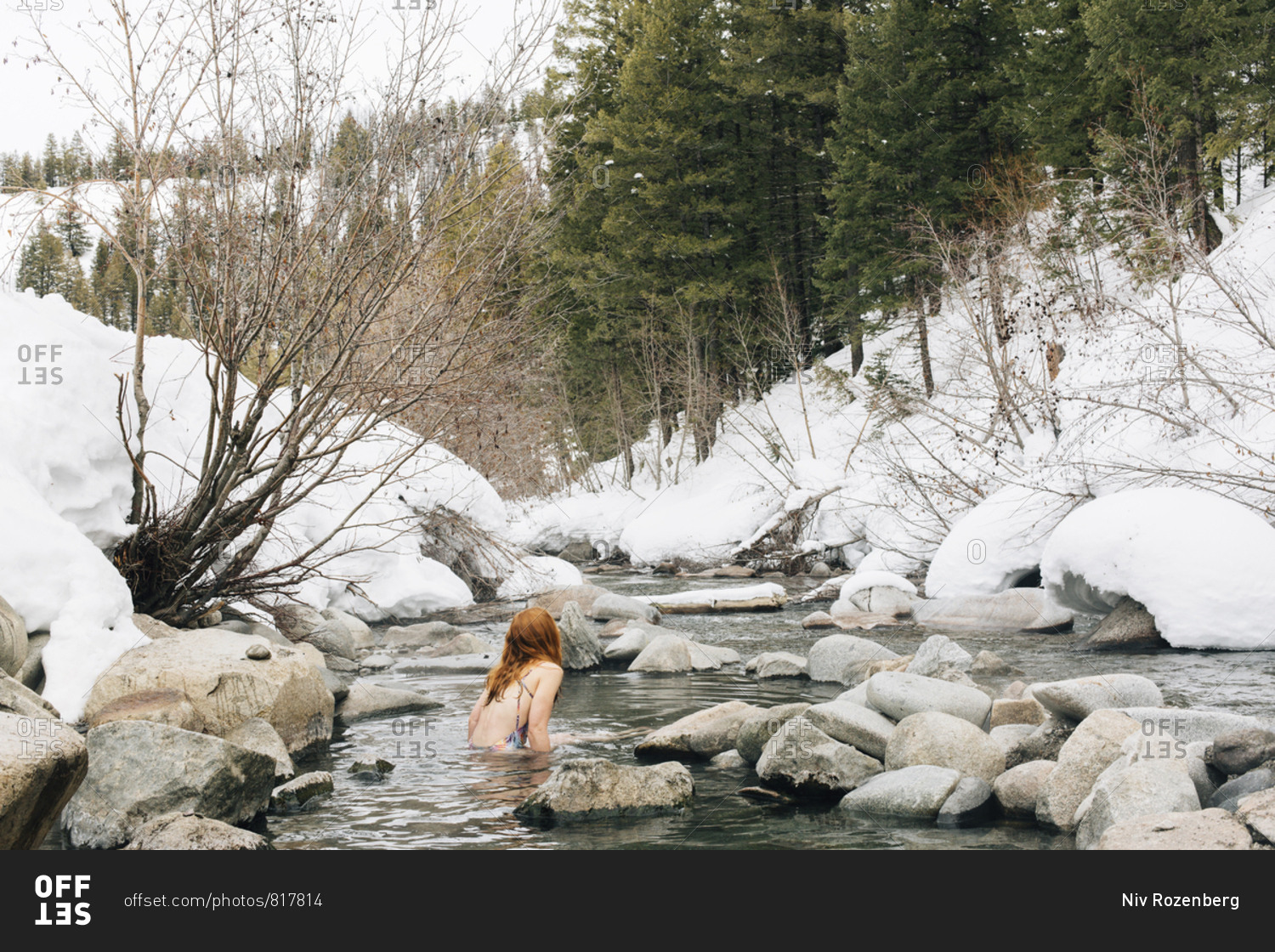 Redhead woman relaxing in a hot spring by snowy river in Sun Valley, Idaho